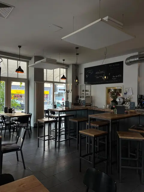 Gastraum des Café Heidelberg mit Hochtischen, Pendelleuchten und der großen Kreidetafel mit dem Schriftzug Heidelberg